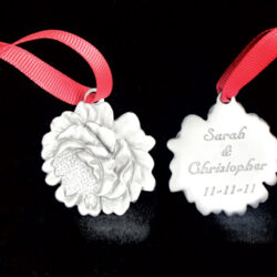 Two pewter flower ornaments with red ribbons.