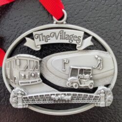 A silver ornament with The Villages logo.